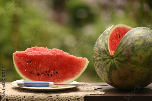 cut ripe big water melon still life with knife on green garden background close up photo photo