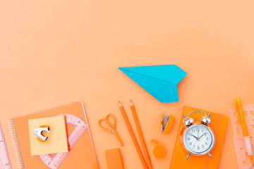 Back to school styled border with school supplies and paper plane on orange background