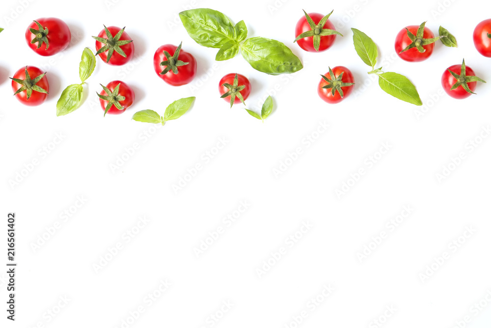 Fototapeta Wiązka soczystych organicznie czerwonych czereśniowych pomidorów w rzędzie z zieloną bazylią opuszcza na białym tle. Błyszczące polerowane błyszczące warzywa. Koncepcja czystego jedzenia. Dieta wegetariańska. Skopiuj miejsce, płaskie świeckich, widok z gó