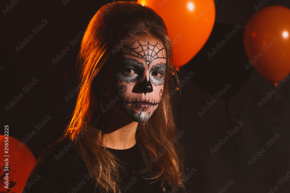 Fototapeta premium Happy Halloween Little cute girl is preparing for Halloween. Having fun with pumpkins on kitchen with cat Halloween makeup.