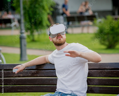 A young man plays a game wearing virtual reality glasses on the street.