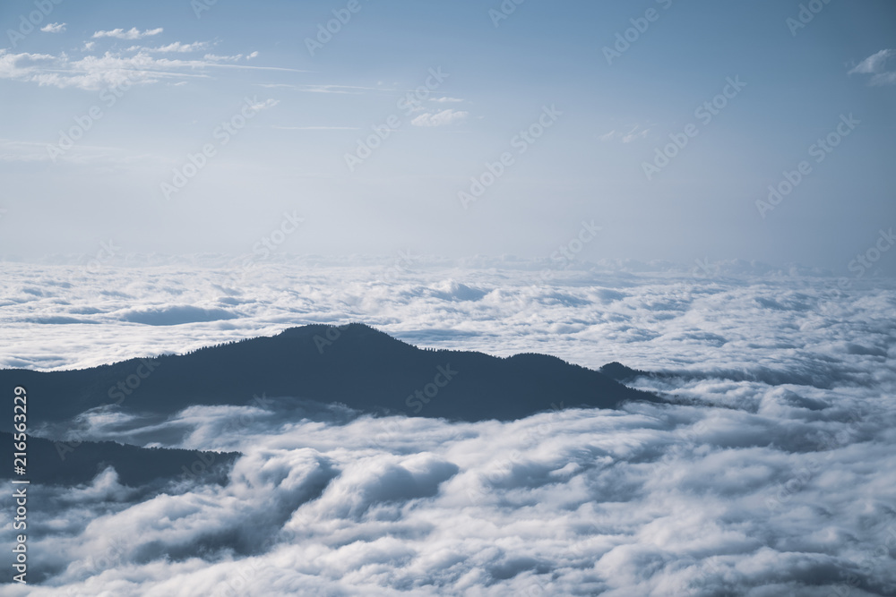 Mountain silhouette above the clouds at sunrise, view from the top view of mountains.