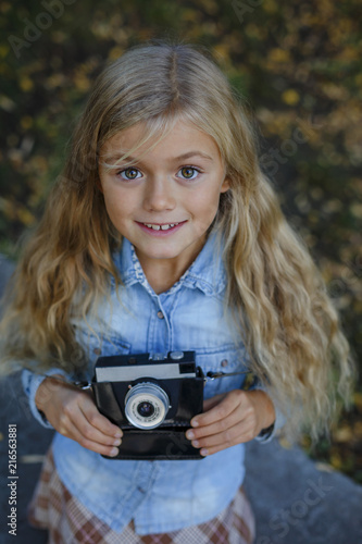 Portrait of pretty little girl with vintage photo camera walking in beautiful park © AnnKot