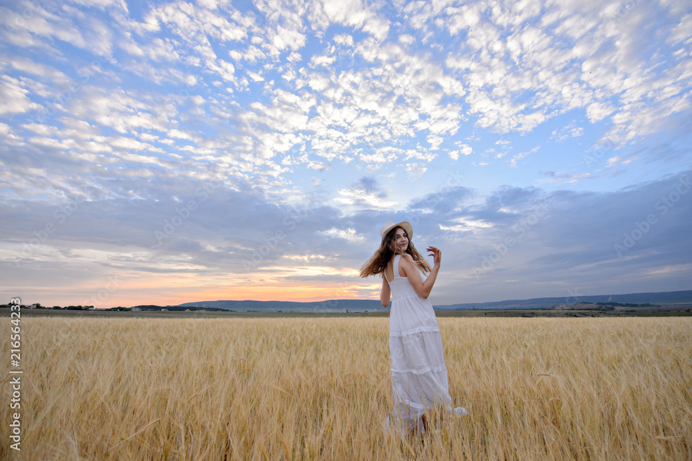 Beautiful woman in a field of rye at sunset. A woman in amazing clothes walking through the field of rye. Beautiful woman in a field of rye at sunset. A woman in amazing clothes walking through the field of rye.