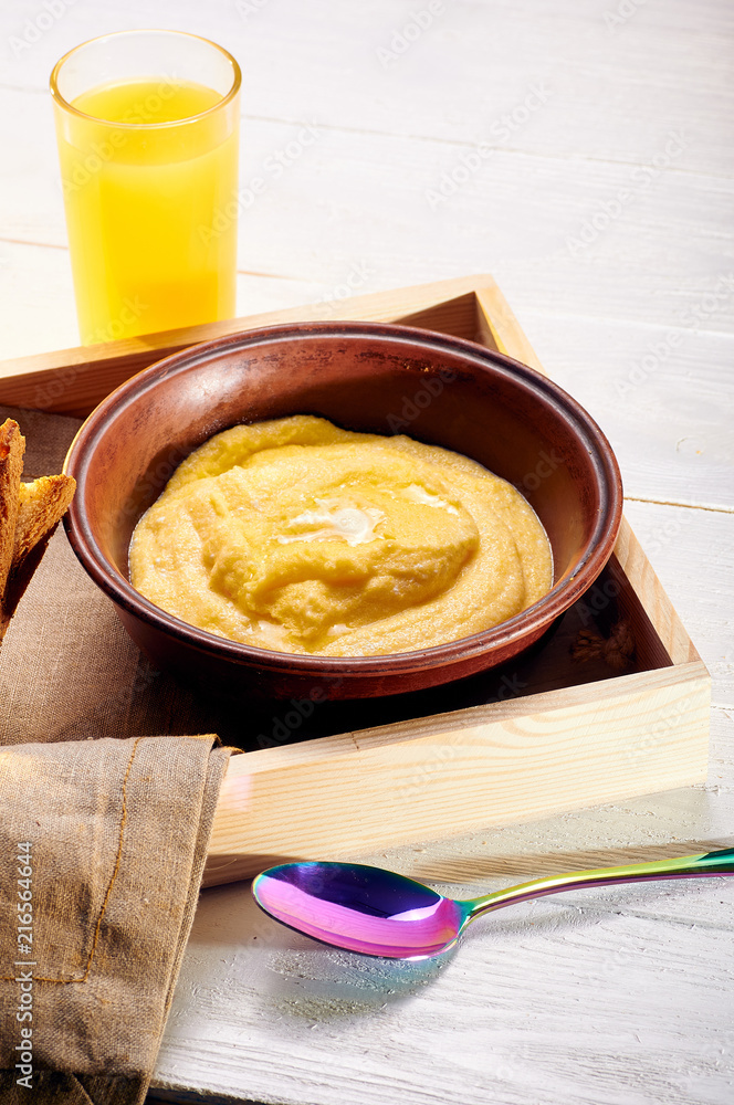 Polenta with butter and some crispy toast. Orange freshly squeezed juice and food on a tray for breakfast in bed. Simple and delicious food for an early morning before work. Polenta with butter and some crispy toast. Orange freshly squeezed juice and food on a tray for breakfast in bed. Simple and delicious food for an early morning before work.