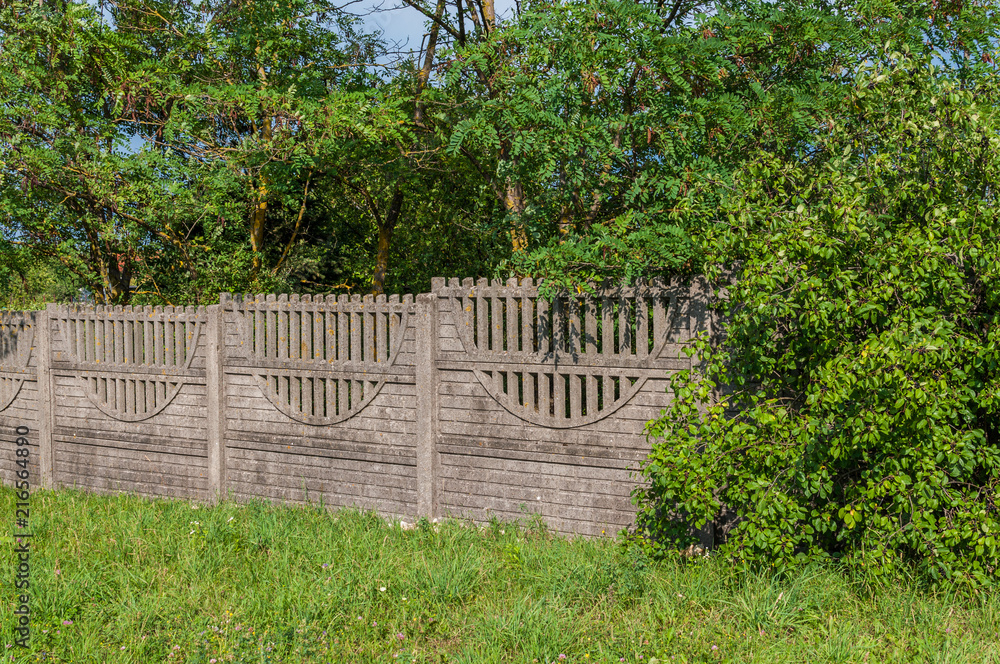 Naklejka premium Betonowe ogrodzenie i zielone drzewa