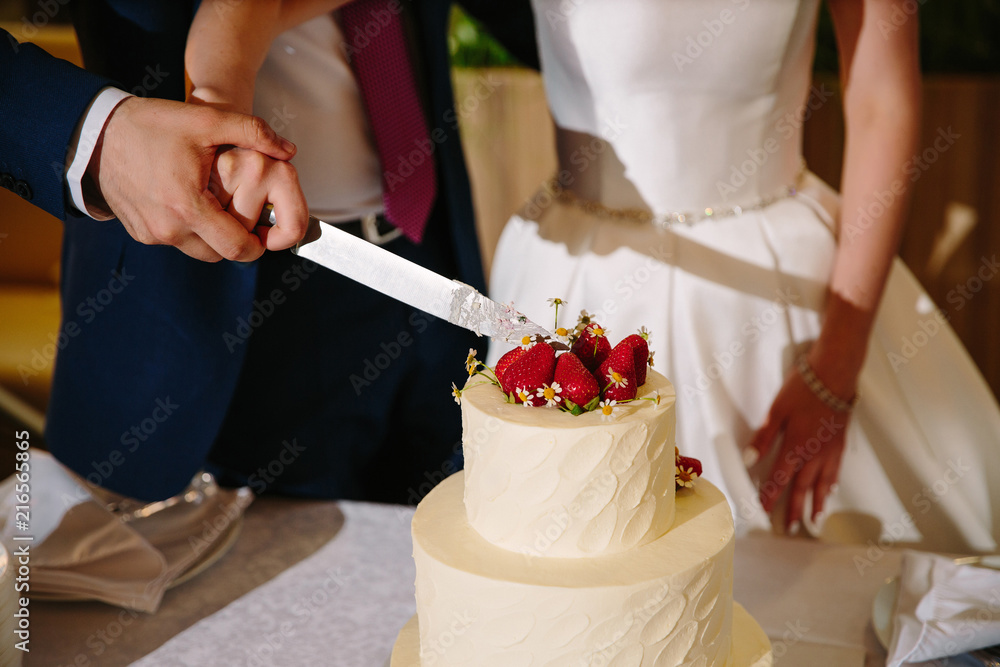 A bride and a groom is cutting their wedding cake A bride and a groom is cutting their wedding cake