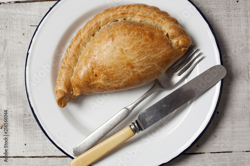 Φωτογραφία A Cornish pasty on a white enamel plate with a knife and fork