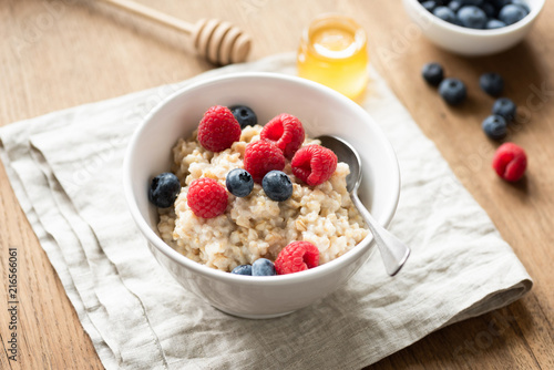Oats porridge with fresh berries in a bowl, selective focus