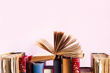 Pile of old vintage books on pink background with copy space on pink background