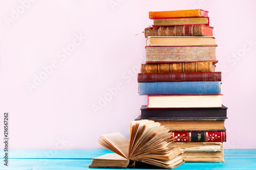 Fotografie Pile of vintage books on blue wooden shelf, copy space on pink wall background