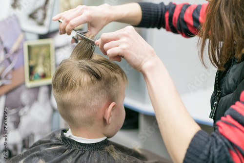 A little boy in a hairdresser. A child is given a haircut on his head.