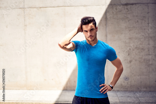 Portrait of handsome and muscular man looking at camera during outdoors workout in the city