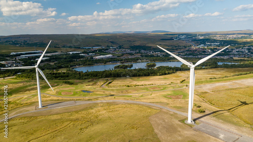 Wind turbines on a rural hillside next to a large lake photo