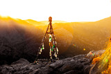 Altitude geodesic mark. The metal structure on the plowed ground on a background of mountains, evening sky and sunset beams
