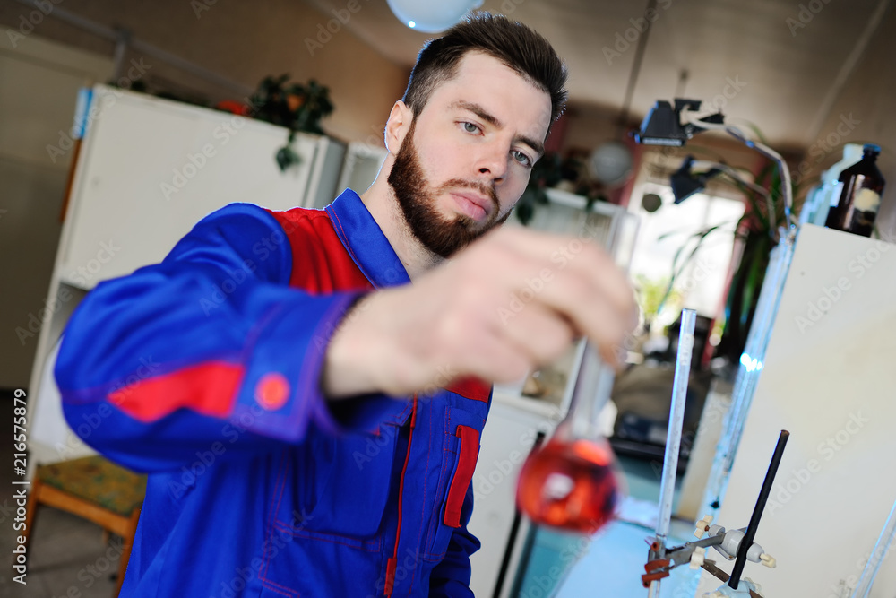 A young pretty scientist working in the laboratory, examines a flask or a test tube with a colored liquid. Chemical industry A young pretty scientist working in the laboratory, examines a flask or a test tube with a colored liquid. Chemical industry