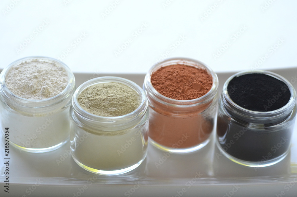 Top view of kaolin powder, activated charcoal, red, green and green cosmetic clays in jars. Deep cleansing bentonite (montmorillonite) clay for beauty spa face mask, body detox and hair treatments. Top view of kaolin powder, activated charcoal, red, green and green cosmetic clays in jars. Deep cleansing bentonite (montmorillonite) clay for beauty spa face mask, body detox and hair treatments.