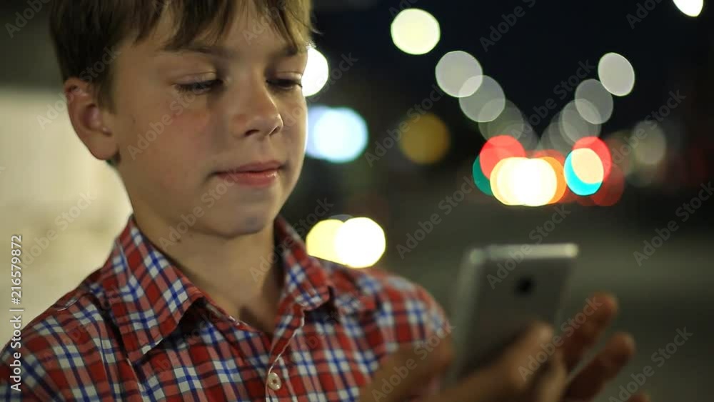 boy with a smartphone in hand on the background of night city lights. boy with a smartphone in hand on the background of night city lights.