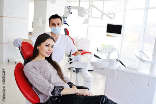 Young beautiful girl in dental chair on background of dentist smiling at camera. Dentistry, snow-white smile, beauty,