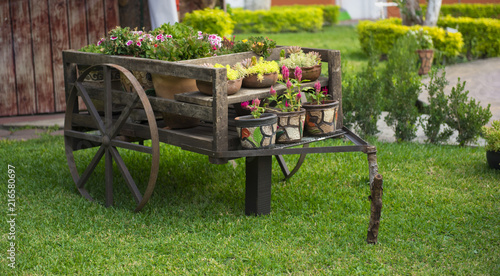 Carreta antigua de madera con flores en jardín
