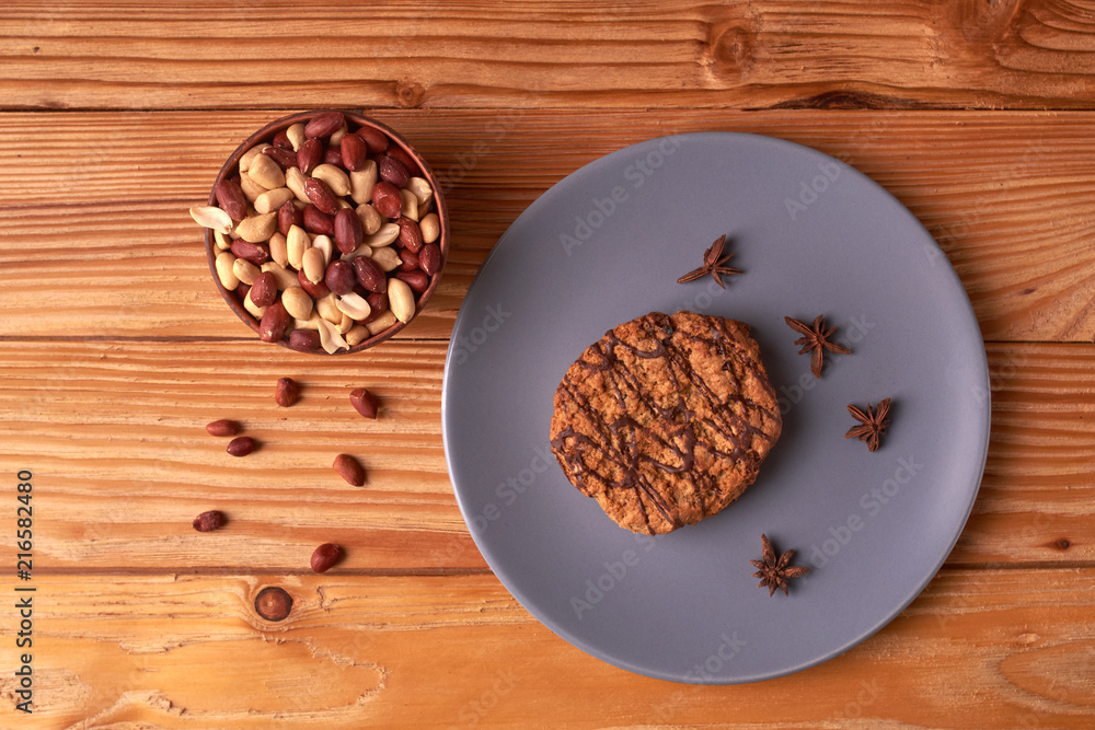 Fried Roasted peanut seed in clay bowl and chocolate cookies on plate. top view Fried Roasted peanut seed in clay bowl and chocolate cookies on plate. top view