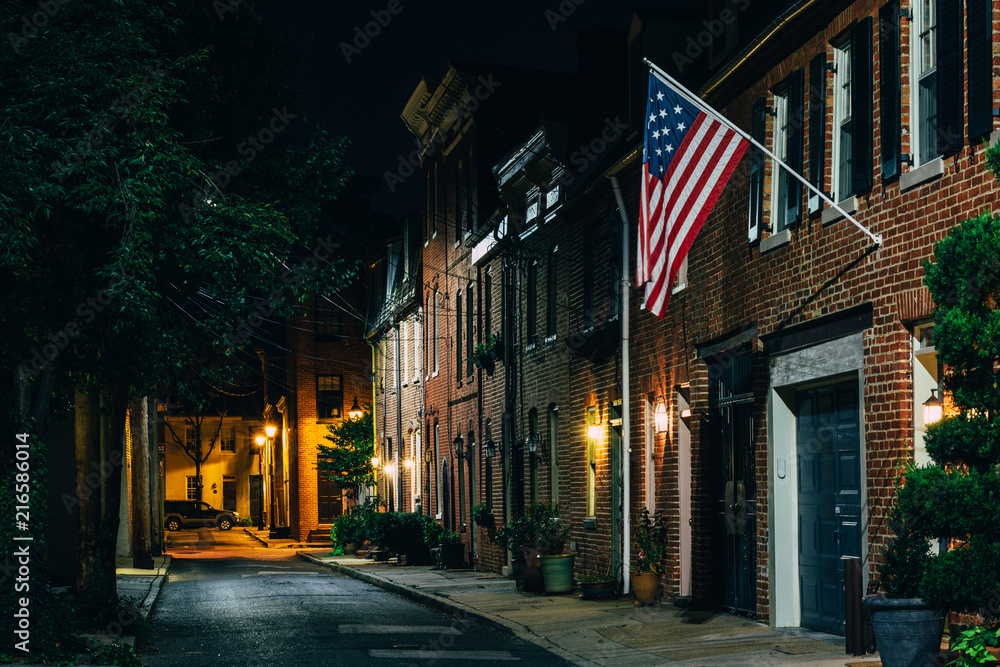 American flag and row houses on Bethel Street at night, in Fells Point, Baltimore, Maryland