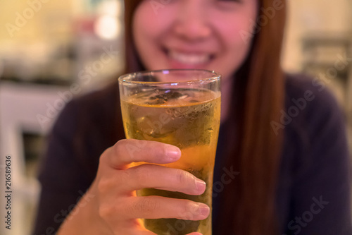 Asian young woman in happiness action and drinking beer in pub and restaurant with low light place, relax and drink concept