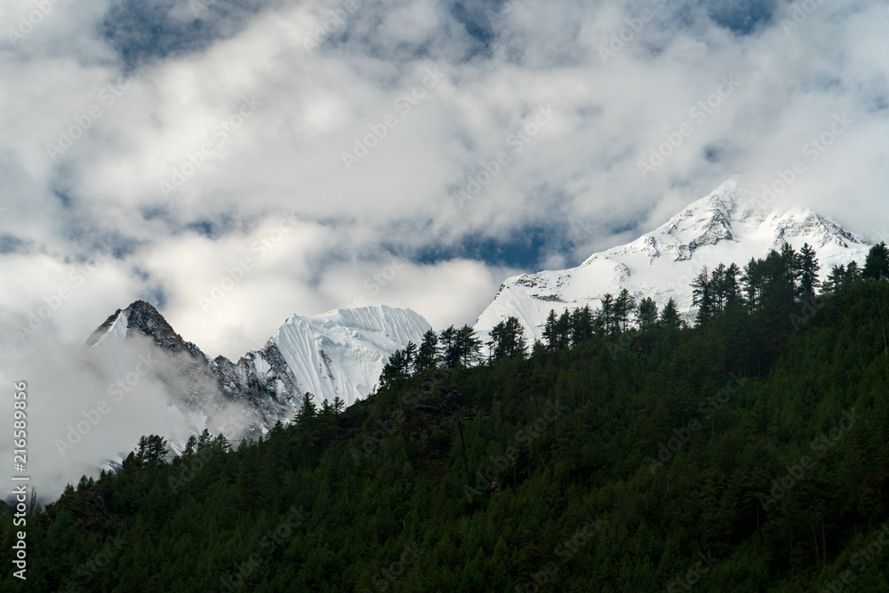 Snow capped peaks rise into the clouds out of site on the Annapurna Circuit