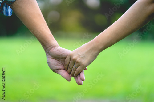 close up hand of female and male holding  together in park © Natsicha