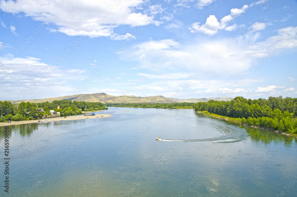 A bird's-eye view of the river, surrounded by forests and hills. Water skiing. View from the bridge to the river. 