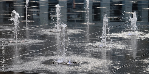 small beautiful fountain in the open air, on the street. Drops of water, jets of water frozen in the air in flight against the backdrop. photo