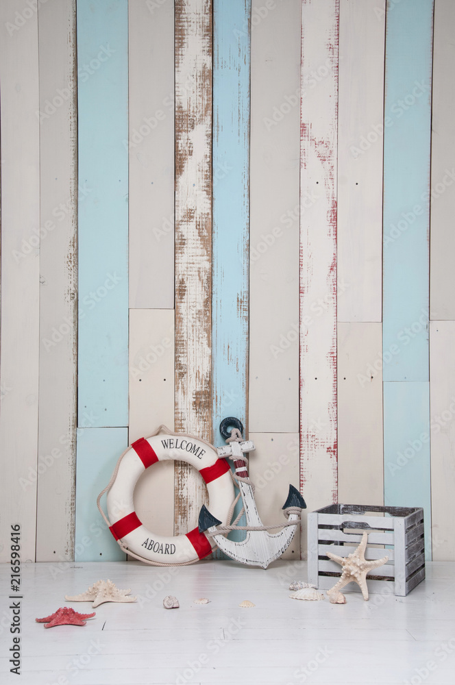 Obraz premium Composition on a marine theme with an anchor and life buoy, seashells and starfish on a wooden background