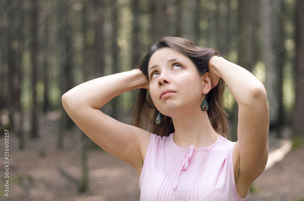 Young pensive woman posing in the forest.