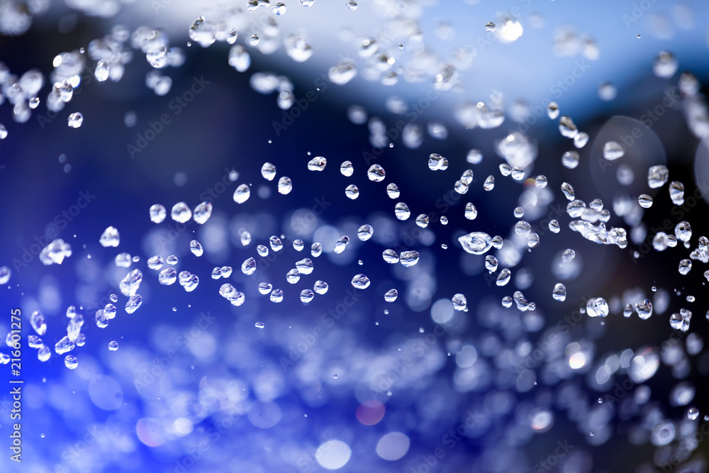 Close up of a water drops on a blue gradient background, covered with drops of water -condensation. Close-up of a drop of a fountain flying upward Close up of a water drops on a blue gradient background, covered with drops of water -condensation. Close-up of a drop of a fountain flying upward