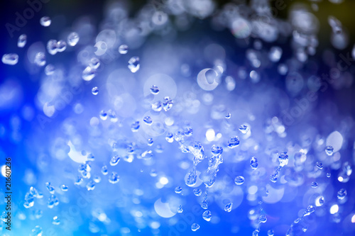 Close up of a water drops on a blue gradient background, covered with drops of water -condensation. Close-up of a drop of a fountain flying upward