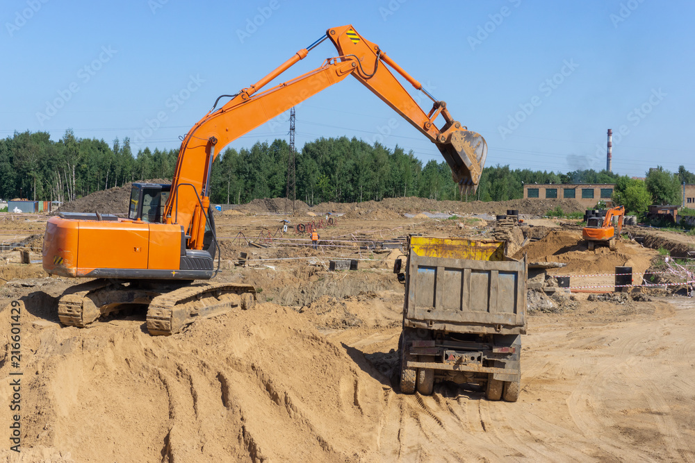 Obraz premium Excavator at the construction site will load the truck with sand