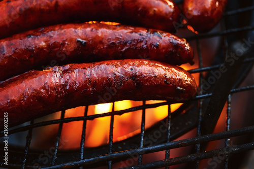 Grilled sausages on grill flames BBQ background