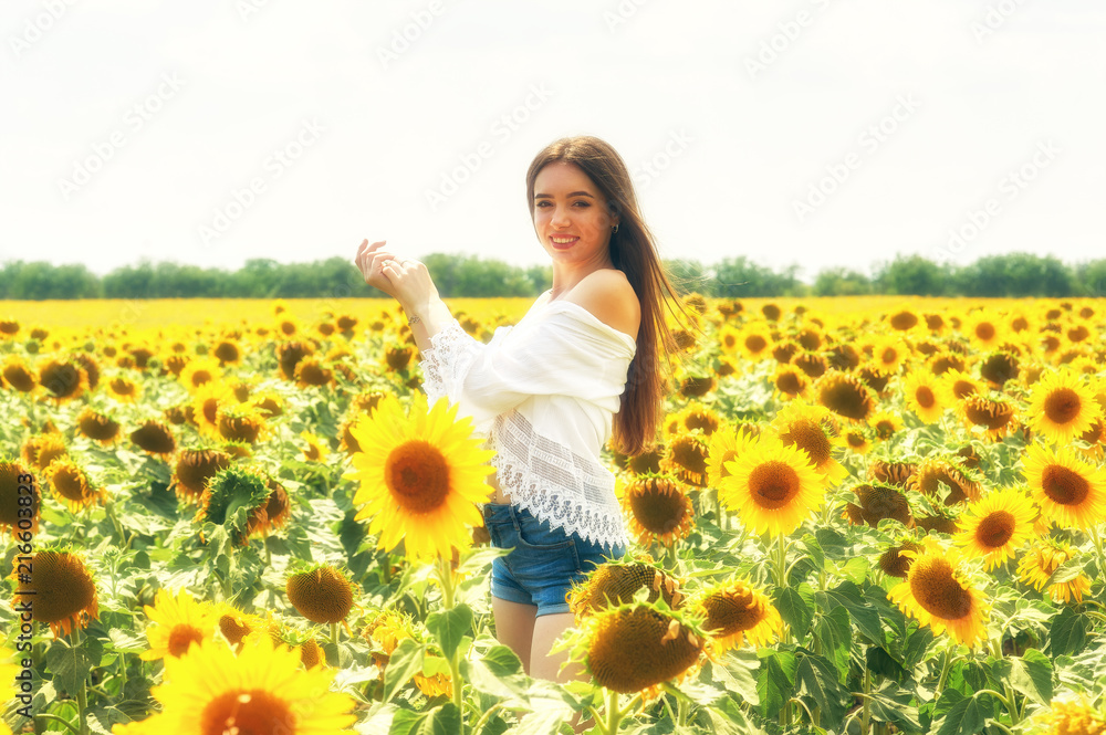 Beautiful young girl outdoors . A young girl is having fun in the field with flowering sunflowers . Beautiful young girl outdoors . A young girl is having fun in the field with flowering sunflowers .