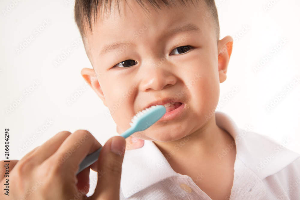 Asian boy take a toothbrush cleaning teeth by his mother Asian boy take a toothbrush cleaning teeth by his mother