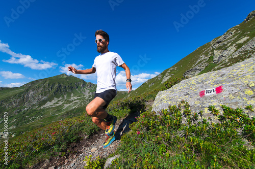 Male athlete practicing mountain running on a trail marked by the orobic alps