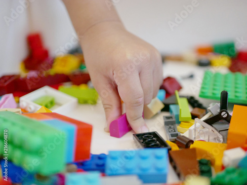 Little baby's hand picking / choosing a piece of colorful interlocking plastic bricks