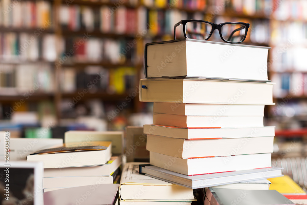 Fototapeta premium glasses on top of stack of books lying on table in bookstore