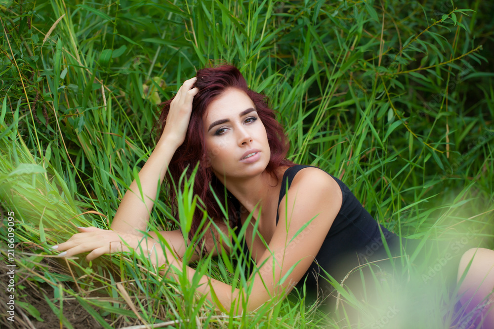 beautiful young sexy woman lies in high grass in a black swimsuit beautiful young sexy woman lies in high grass in a black swimsuit