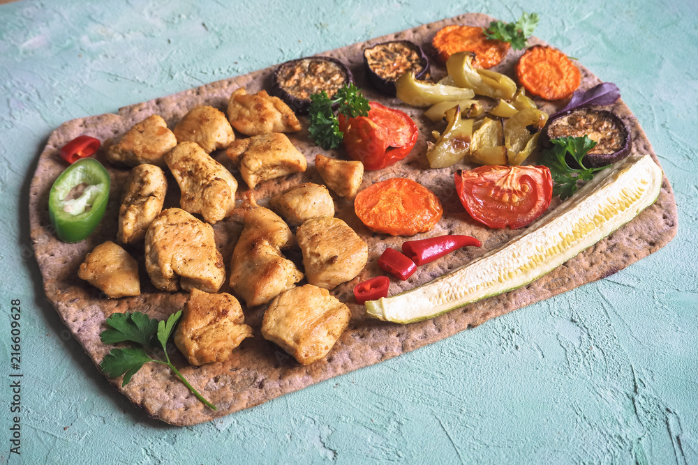 Fototapeta premium Grilled chicken pieces with vegetables on thin bread. 