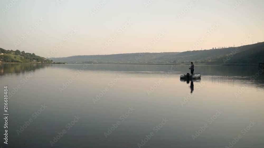 The fisherman is fishing on the river from the boat. The fisherman is fishing on the river from the boat.