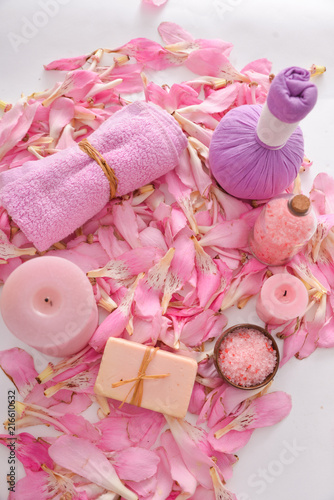 Many pink tropical petals and candle ,soap ,herbal ball,towel , ,salt in bowl ,candle