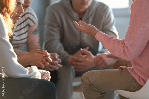 Fotografering Close-up of a therapist gesticulating while talking to a group of listing teenagers during an educational self-acceptance and motivation meeting