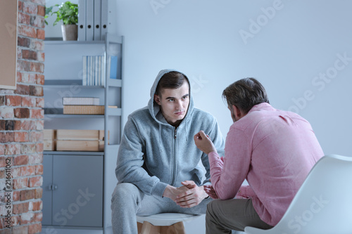 A psychology specialist explaining an action plan for recovery to a troubled teenage boy during an individual therapy session. photo