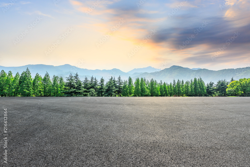 Fototapeta premium Empty asphalt square and mountain with forest scenery at sunrise
