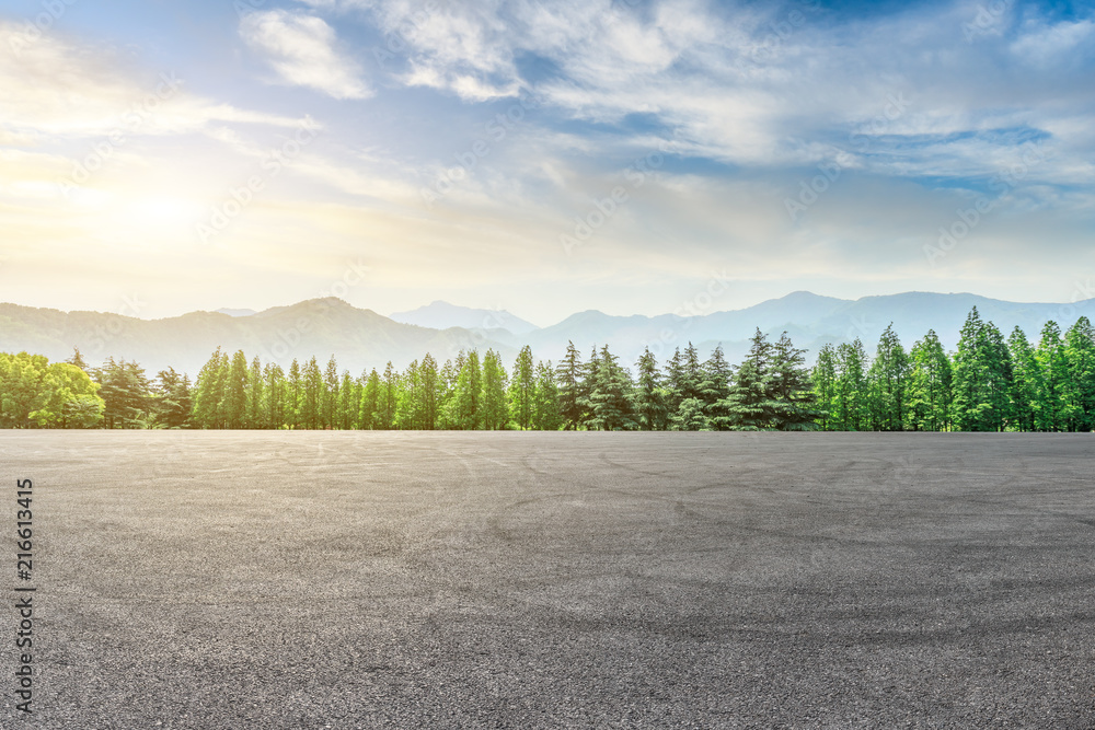 Fototapeta premium Empty asphalt square and mountain with forest scenery at sunrise